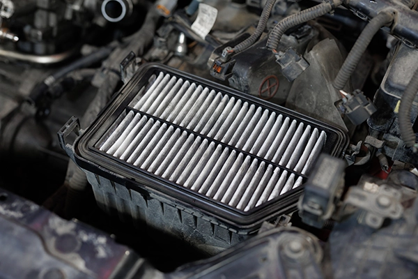 Contaminated engine air filter with cover removed in engine bay
